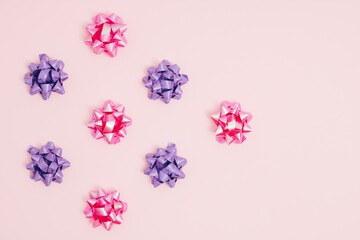 Purple and pink ribbons bowed in the form of a flower isolated on a pastel pink background. Fashion, holiday, gift concept. Flat lay.
