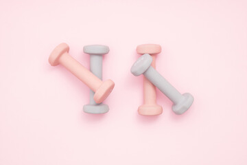 Four pastel color exercise weights on pastel pink background with soft shadow. Exercise, healty lifestyle or New Year resolution concept. Flat lay.