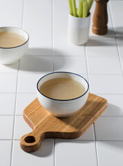 Homemade bone broth in a white bowl on a wooden board. The concept of a healthy diet. 