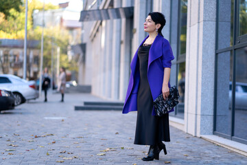 An elegant woman in a stylish outfit poses on a city street