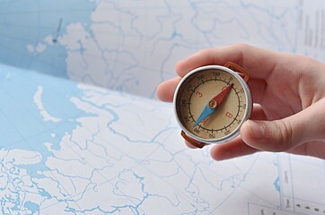 hand holding a compass on the background of a contour map