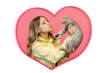 A young caucasian cute blonde woman in a yellow shirt holds a cat in her hands admiring it inside a heart-shaped frame on a pink background. The girl babying with a kitten. Fiendship of pet and owner