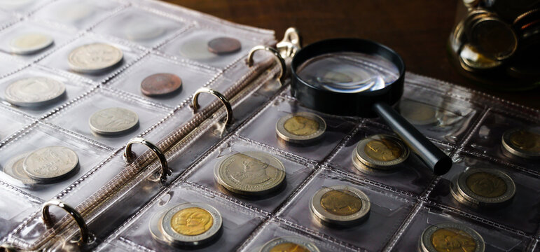 Old collectible coins on a wooden table. Dark background. Banner. Numismatics, Coins in the album. Selective focus.                                                                