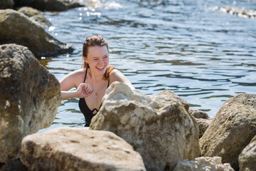 Girl comes out from sea on rocky coast