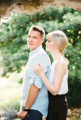 Woman hugs from behind a man on a green tree background