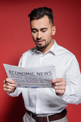 bearded businessman in white shirt reading economic news on red.