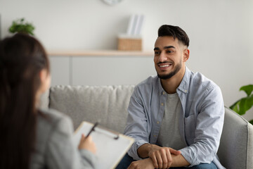 Effective psychotherapy. Happy middle eastern man talking to his psychologist, sharing therapy results with counselor - obrazy, fototapety, plakaty