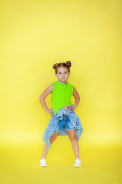 Funny little blonde girl of 6 years old in everyday bright clothes posing alone on the yellow background of the studio. The concept of a child's lifestyle. Location of the copy space. .Background for 