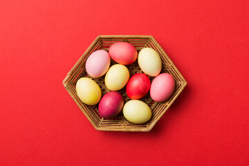 Multi colors Easter eggs in the woven basket on colored background . Pastel color Easter eggs. holiday concept with copy space