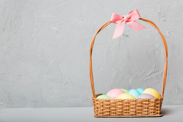 Multi colors Easter eggs in the woven basket on colored background . Pastel color Easter eggs. holiday concept with copy space