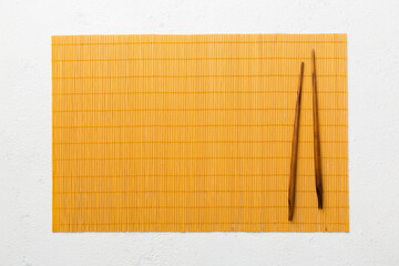 Two chopsticks and bamboo mat on cement background. Top view, copy space
