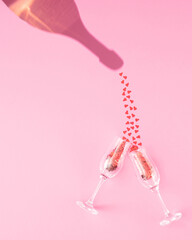Valentine's Day love.celebration artistic concept of.the shadow of a bottle of champagne pouring hearts into two glass cups on pink pastel background. Minimal layout. Flat lay. © StefanVitkovic