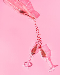 Valentine's Day love.celebration scene of.the glass bottle pouring neatly arranged hearts into two champagne or wine glass cups on pink pastel background. Minimal layout. Flat lay.