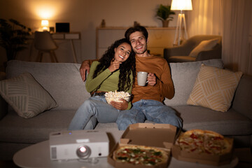 Couple Watching Film Sitting At Desk With Pizza Relaxing Indoor