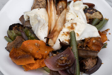 Vegetarian cuisine. Gourmet salad. Top view of a grilled vegetables salad with Italian burrata cheese on a white bowl.