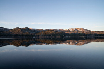 Alpine landscape at nightfall. Magical view of the Andes mountains, forest and lake at sunset. Beautiful symmetrical reflection in the water.