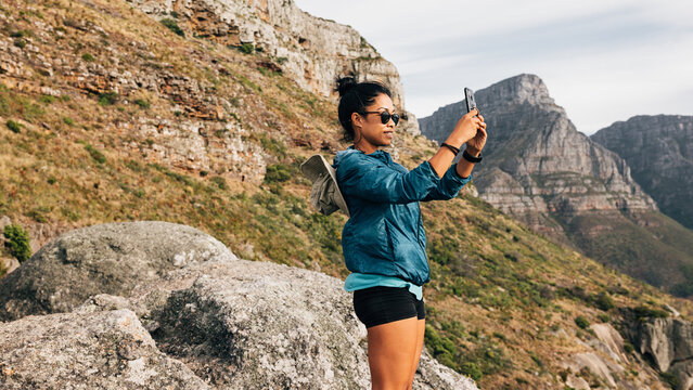 Tourist woman doing nature photography on a smartphone. Female hiker shoots video for social media.