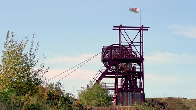 Coal Pit head wheel in operation at an anthracite coal mine in the South Wales valleys with a welsh flag blowing in the wind 