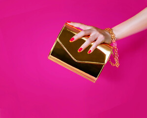 Gold handbag, holding by  girl's hand.
Beautiful manicured nails and gold chain