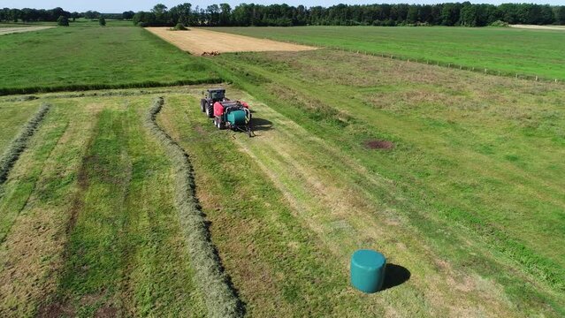 Treker mit einer Stroh Festkammerpresse bei der Strohernte auf einem gem&auml;hten Feld