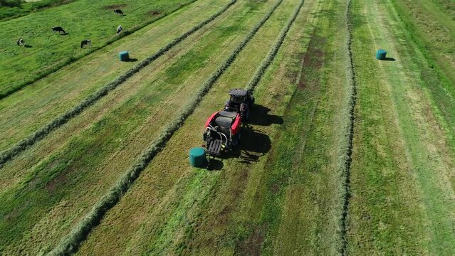 Treker mit einer Stroh Festkammerpresse bei der Strohernte auf einem gem&auml;hten Feld