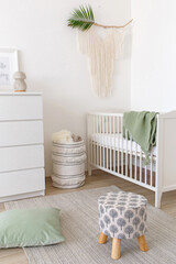 White stylish modern scandi baby's room interior with baby bed and chest of drawers. Children's room interior decor in white and green colors.