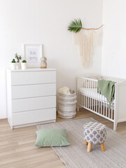 White stylish modern scandi baby's room interior with baby bed and chest of drawers. Children's...
