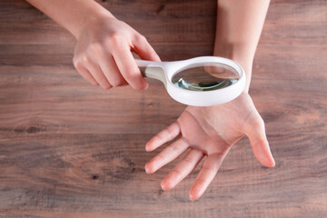 woman examining her nails with a magnifying glass