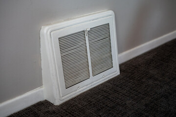 Air vent inside a residential home with carpet and baseboards