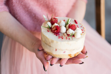 Woman holding raspberry cake stuffed with whipped cream