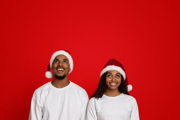 Fototapeta premium Cheerful african american couple looking up at copy space