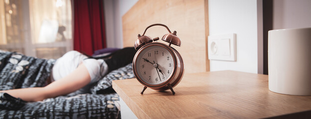 girl sleeping in bed set alarm clock - obrazy, fototapety, plakaty