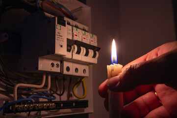 Burning candle near the electrical fuses. Blackout city, electricity off, energy crisis or power...