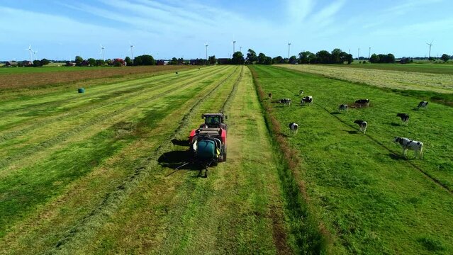 Treker mit einer Stroh Festkammerpresse bei der Strohernte auf einem gem&auml;hten Feld