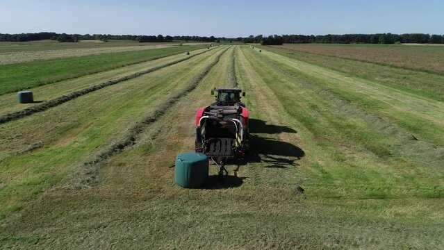 Treker mit einer Stroh Festkammerpresse bei der Strohernte auf einem gem&auml;hten Feld