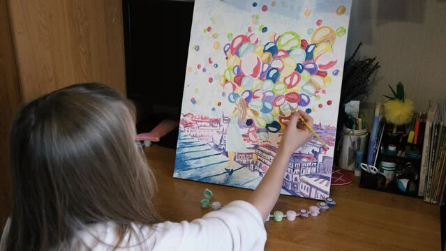 The girl picks up paint with a paintbrush and paints a picture by numbers. Painting for beginners.