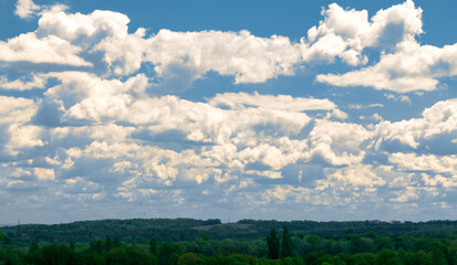 Fototapeta na wymiar Blue sky with fluffy white clouds. Wide green field under cloudy sky
