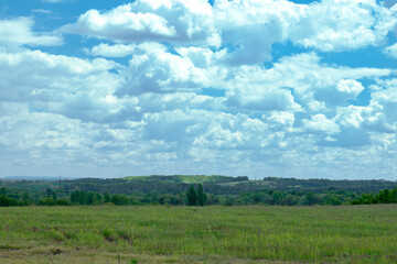 Wide green field under cloudy sky. Blue sky with fluffy white clouds