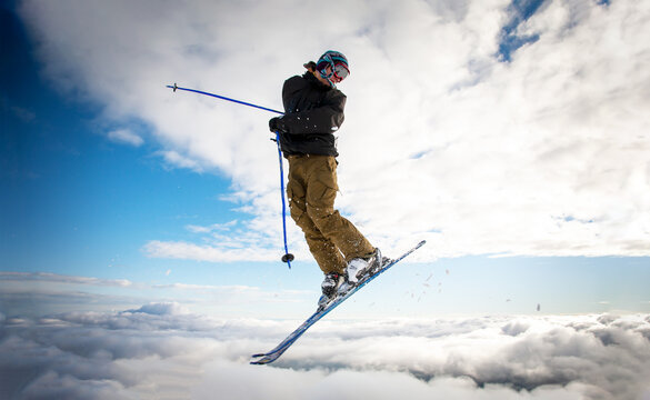 Skier in flight after jumping. Cloudy sky in background.