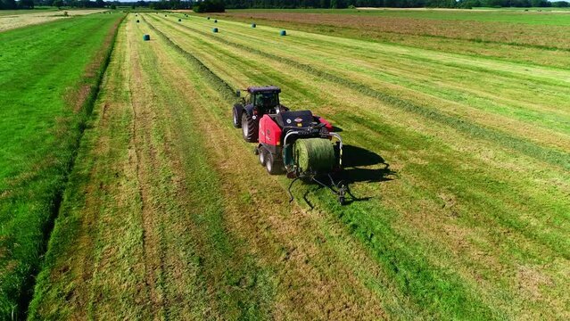 Treker mit einer Stroh Festkammerpresse bei der Strohernte auf einem gem&auml;hten Feld