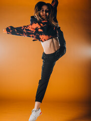 Fototapeta na wymiar Young dance artist perform acrobat moves isolated on orange background