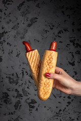Two grilled french hot dogs in woman's hand, fast food and junk food concept, Street food