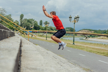 Fototapeta na wymiar Side view picture of an active male athlete jumping up on stairs in outdoor training. .