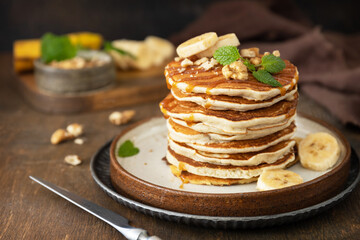 Celebrating Pancake day, american breakfast. Delicious homemade banana pancakes with nuts and caramel on rustic wooden table. - Powered by Adobe