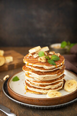 Celebrating Pancake day, american breakfast. Delicious homemade banana pancakes with nuts and caramel on rustic wooden table. Copy space.