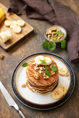 Celebrating Pancake day, american breakfast. Delicious homemade banana pancakes with nuts and caramel on rustic wooden table.