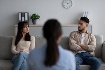 Back view of female psychologist giving therapy session to arab couple sitting on couch and looking at each other - obrazy, fototapety, plakaty