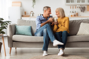 Happy Senior Couple Drinking Coffee Holding Mugs Sitting At Home