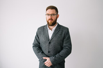 Handsome man with beard wearing business jacket and glasses looking to camera, serious profile pose with natural face standing on white background and posing in studio. Copy space