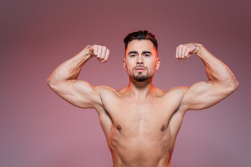 lighting on shirtless man showing muscles on pink and grey.